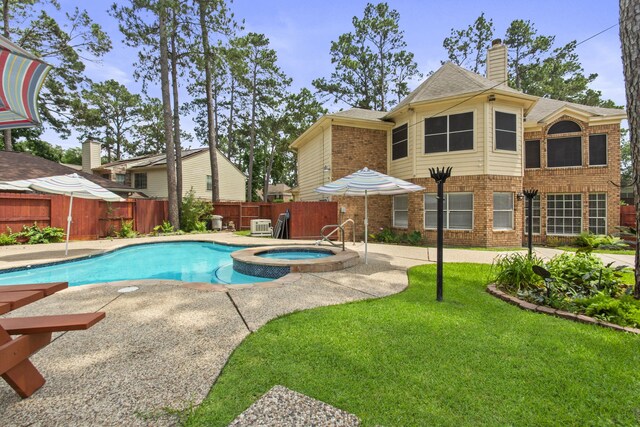 view of swimming pool featuring a lawn, a patio, a pool with connected hot tub, and a fenced backyard