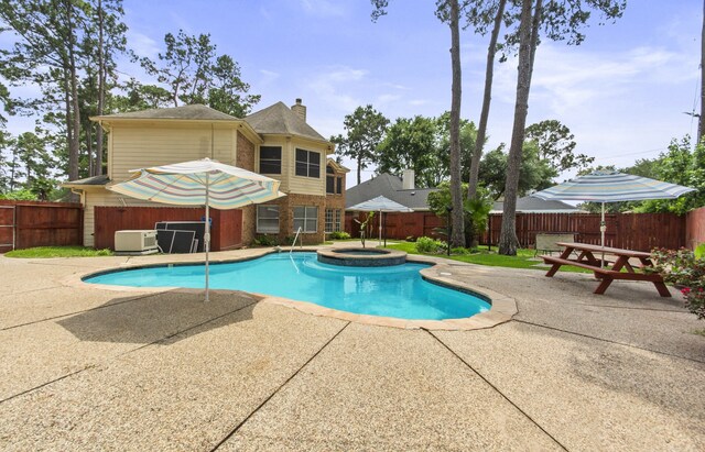 view of swimming pool with a fenced backyard, a pool with connected hot tub, and a patio area