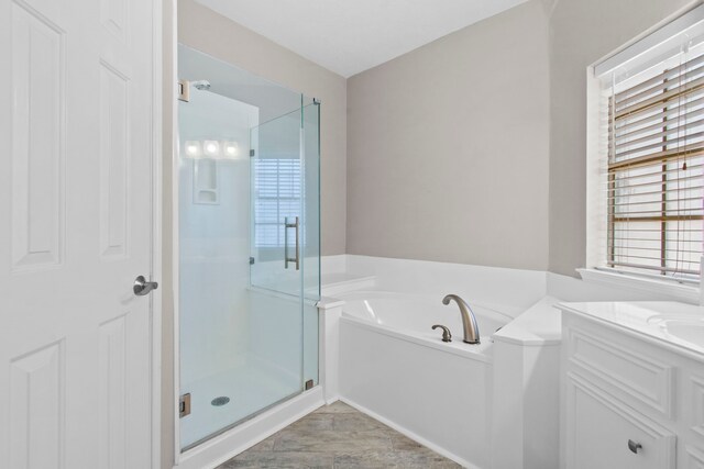 bathroom with plenty of natural light, a stall shower, a bath, and vanity