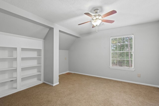 bonus room featuring carpet floors, a textured ceiling, ceiling fan, and baseboards