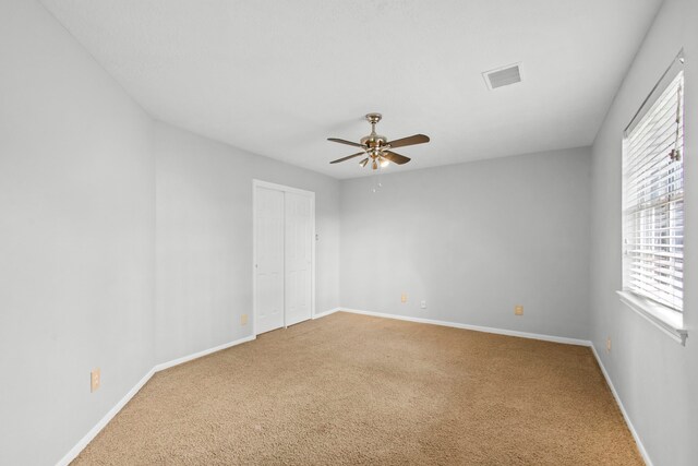 spare room featuring visible vents, carpet, and a wealth of natural light