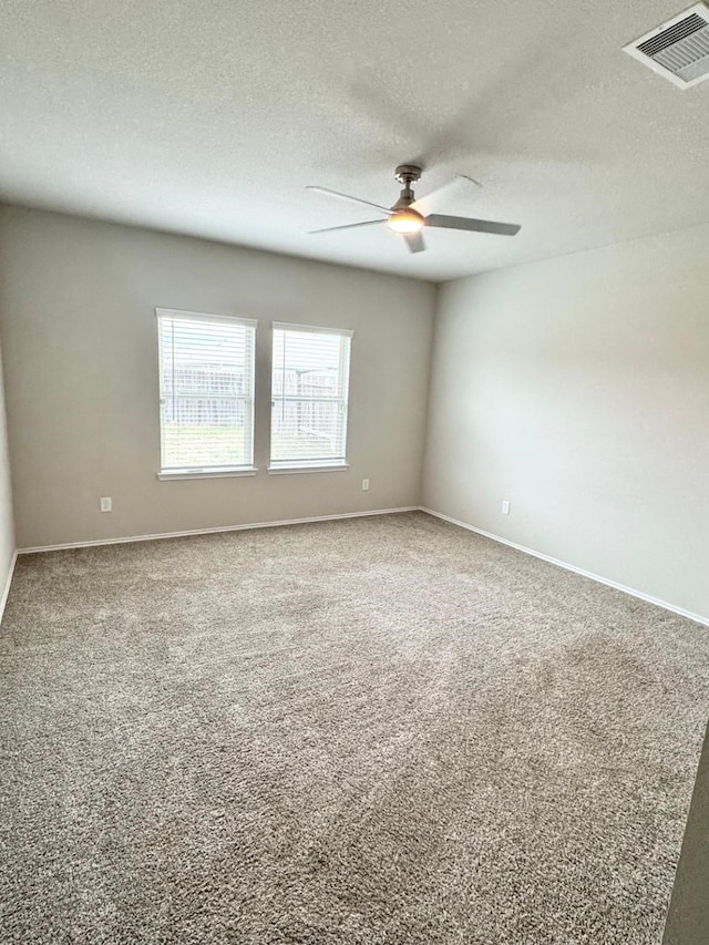 carpeted spare room featuring baseboards, a textured ceiling, visible vents, and a ceiling fan