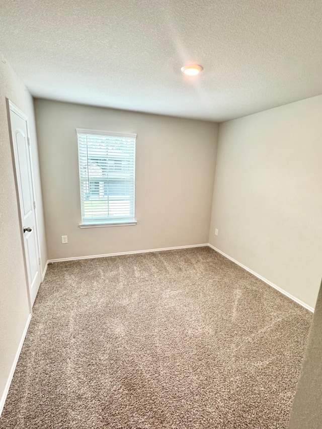 carpeted empty room with baseboards and a textured ceiling