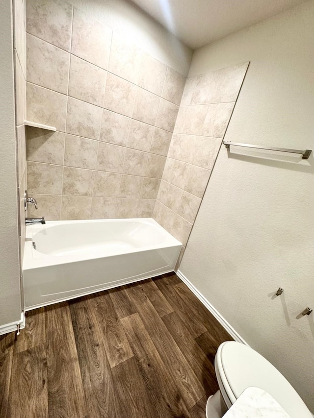 bathroom featuring toilet, baseboards, bathtub / shower combination, and wood finished floors