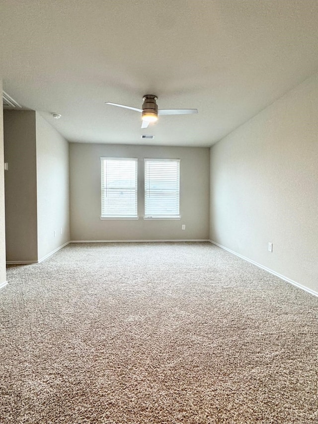 carpeted empty room featuring baseboards, a textured ceiling, visible vents, and a ceiling fan