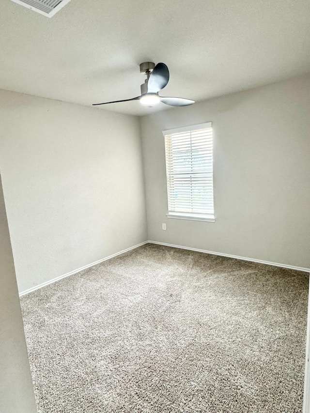 spare room featuring a ceiling fan, carpet, baseboards, and visible vents