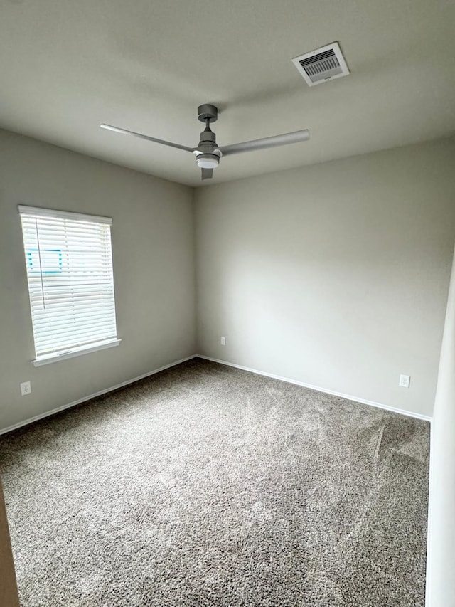 empty room featuring carpet, baseboards, visible vents, and a ceiling fan