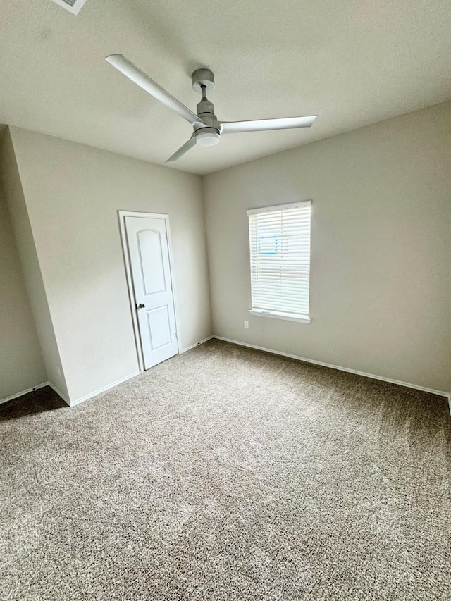 carpeted empty room with baseboards and a ceiling fan