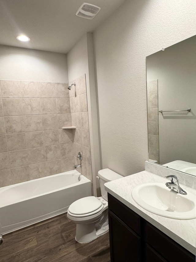 bathroom with vanity, toilet, visible vents, washtub / shower combination, and wood finished floors