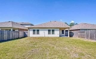back of property with a fenced backyard and a yard