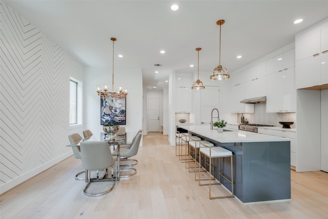 2113 Huldy St, Houston, TX 77019 - kitchen featuring modern cabinets, white cabinets, under cabinet range hood, light wood finished floors, and a sink