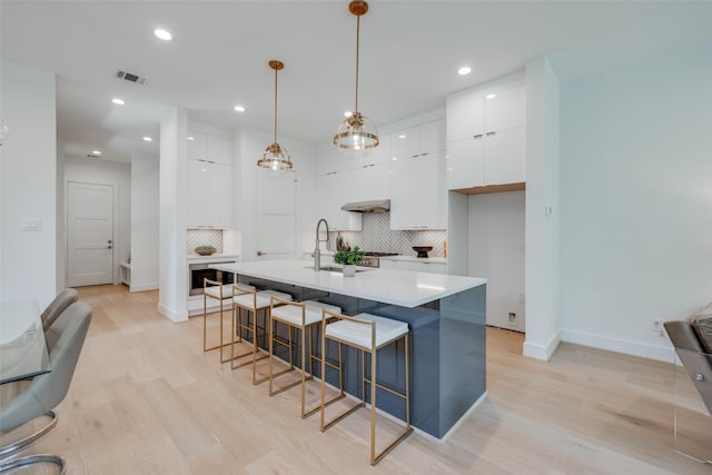 2113 Huldy St, Houston, TX 77019 - kitchen featuring modern cabinets, white cabinetry, a breakfast bar area, tasteful backsplash, and recessed lighting