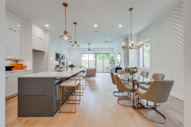 2113 Huldy St, Houston, TX 77019 - kitchen with an accent wall, modern cabinets, white cabinetry, light wood finished floors, and recessed lighting