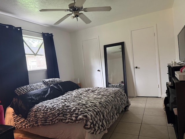 bedroom featuring a textured ceiling, a ceiling fan, and light tile patterned floors