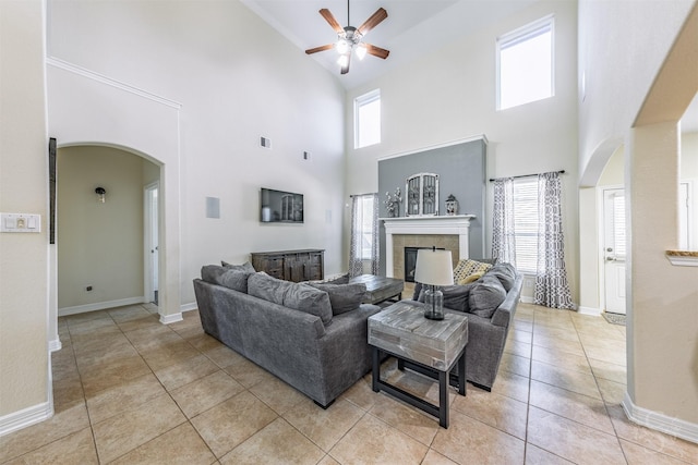 6522 Tamarind Sky Ln, Fulshear, TX 77441 - living room with arched walkways, a ceiling fan, high vaulted ceiling, a fireplace, and light tile patterned floors