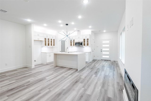 5304 Lynnfield St, Houston, TX 77028 - kitchen with stainless steel microwave, recessed lighting, white cabinetry, a center island with sink, and light wood-type flooring