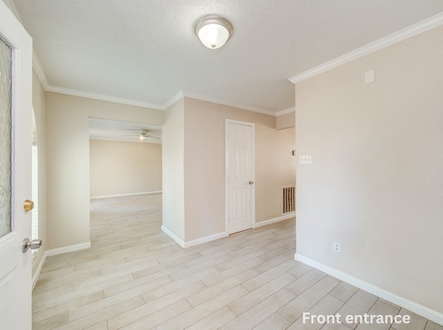 empty room featuring baseboards, crown molding, and light wood finished floors