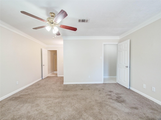 empty room with visible vents, crown molding, baseboards, carpet flooring, and ceiling fan