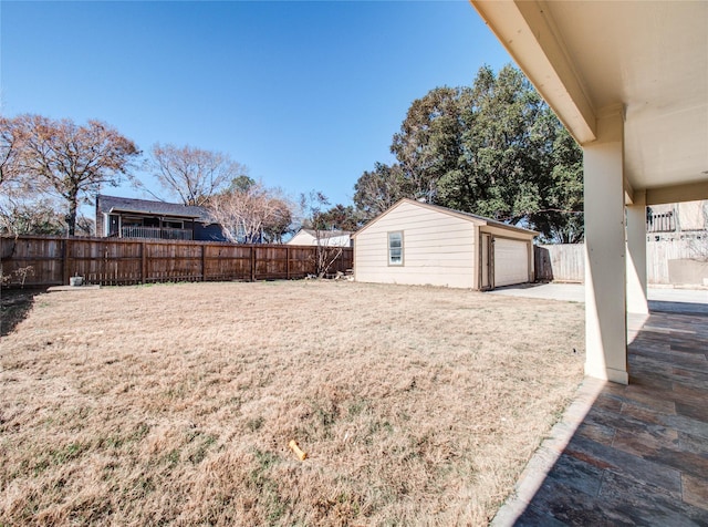 view of yard with a fenced backyard, an outbuilding, and a garage