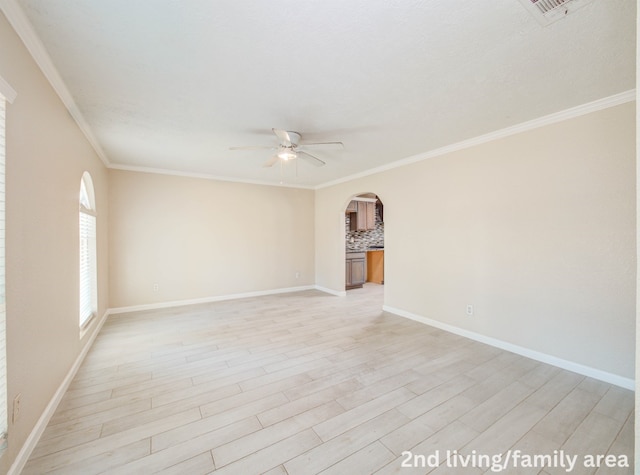 unfurnished room with arched walkways, baseboards, light wood-style floors, a ceiling fan, and crown molding