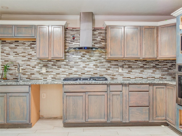 kitchen with wall chimney exhaust hood, a sink, backsplash, and light stone counters