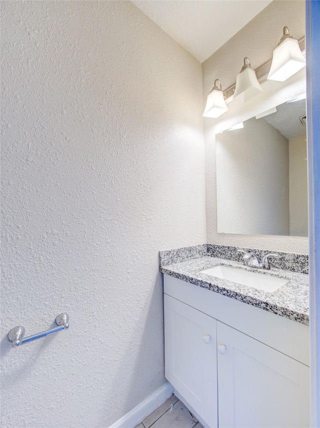 bathroom featuring a textured wall and vanity