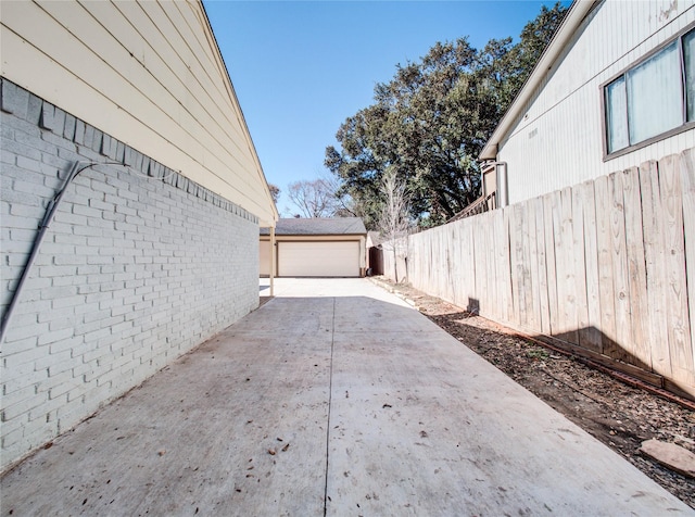 view of side of home with fence, an outbuilding, brick siding, and a detached garage