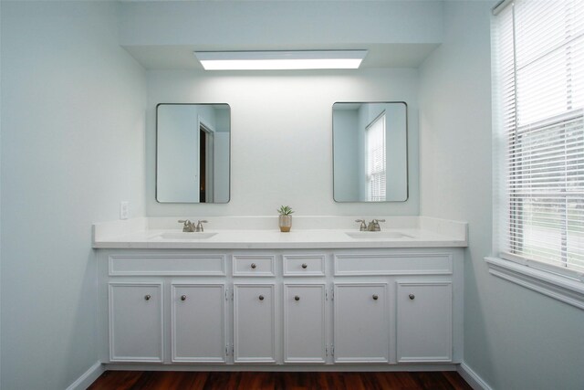 full bathroom featuring double vanity, baseboards, and wood finished floors