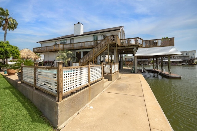 dock area featuring a deck with water view, boat lift, and a swimming pool