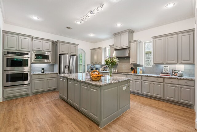 114 Pacific Grove Dr, Montgomery, TX 77316 - kitchen featuring decorative backsplash, appliances with stainless steel finishes, a center island with sink, and gray cabinetry