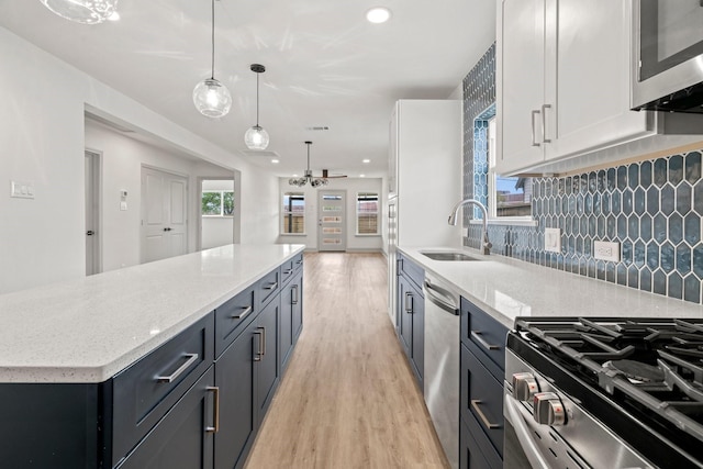 1009 Genova St, Houston, TX 77009 - kitchen with a sink, appliances with stainless steel finishes, light wood-style floors, ceiling fan, and backsplash