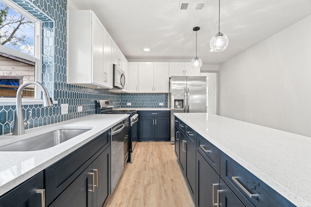 1009 Genova St, Houston, TX 77009 - kitchen featuring a sink, appliances with stainless steel finishes, light wood-style flooring, and white cabinetry