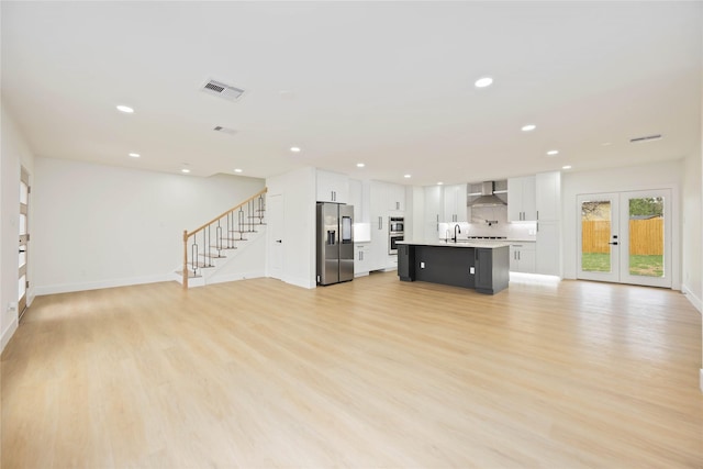 unfurnished living room featuring visible vents, recessed lighting, stairway, light wood-type flooring, and french doors