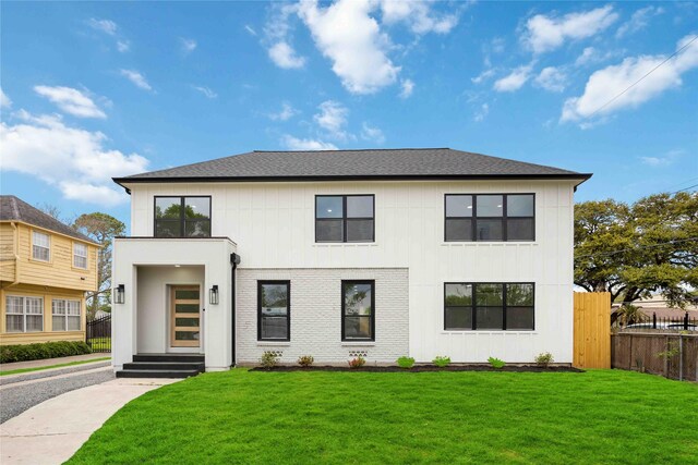 modern inspired farmhouse with a front lawn, a shingled roof, entry steps, and fence