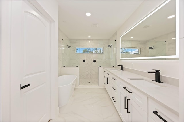 bathroom with marble finish floor, a freestanding bath, a sink, and a marble finish shower