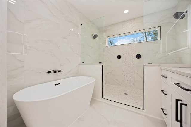 full bath with tile walls, marble finish floor, a freestanding tub, vanity, and a walk in shower