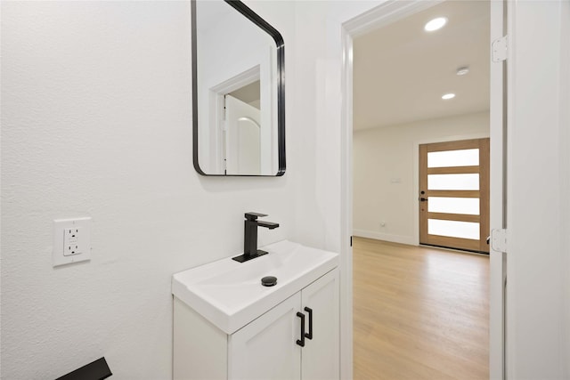 bathroom with vanity, baseboards, recessed lighting, and wood finished floors
