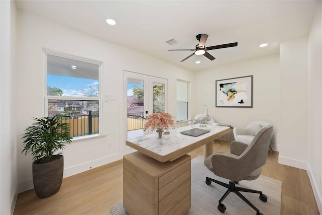 office featuring baseboards, a ceiling fan, visible vents, and light wood-type flooring