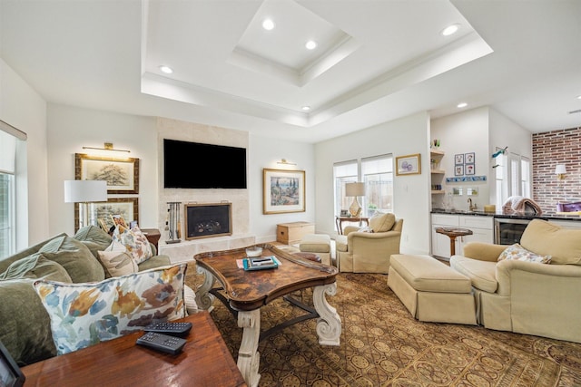 living area featuring recessed lighting, a raised ceiling, a high end fireplace, and ornamental molding