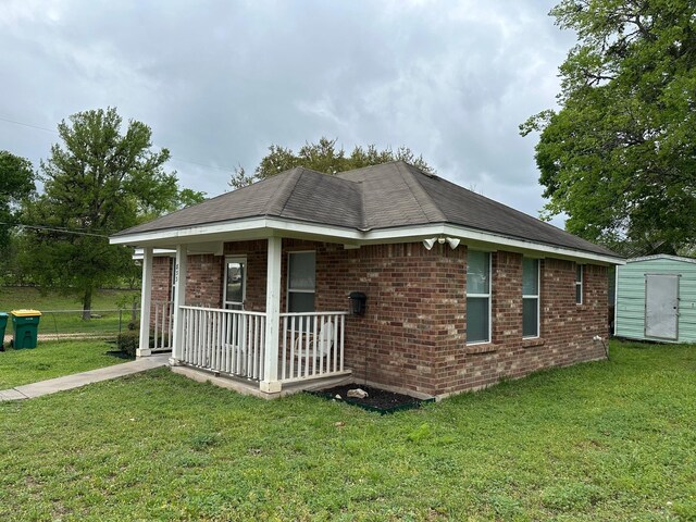 833 E Camp St, La Grange, TX 78945 - view of side of property featuring covered porch, a storage shed, brick siding, and a lawn