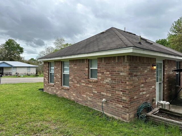 833 E Camp St, La Grange, TX 78945 - view of home's exterior featuring brick siding, roof with shingles, and a lawn