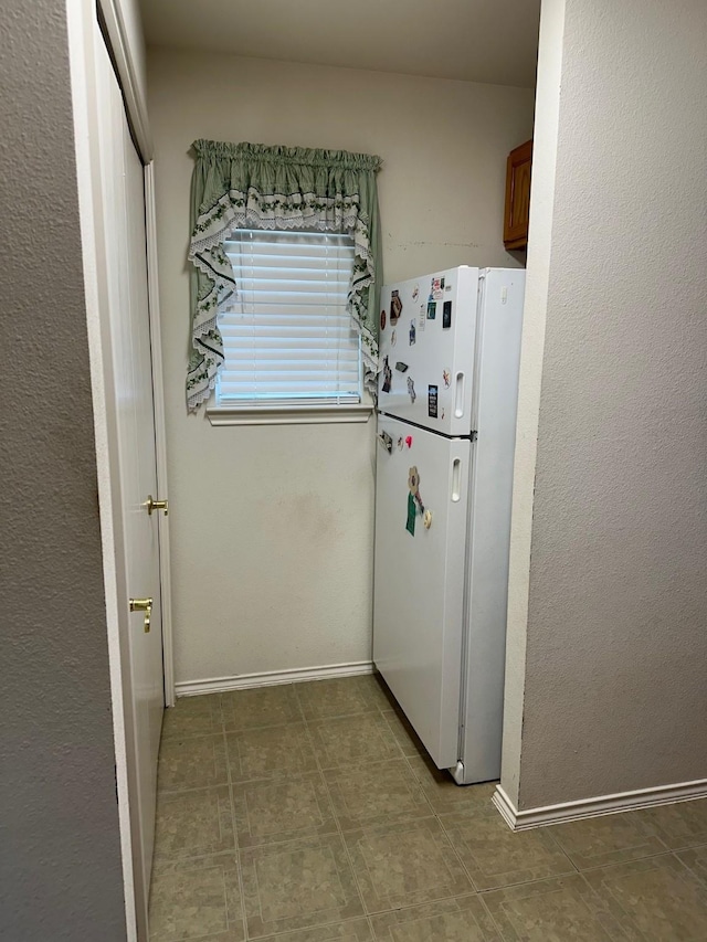 833 E Camp St, La Grange, TX 78945 - kitchen with freestanding refrigerator, brown cabinetry, and baseboards