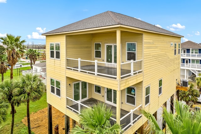 rear view of house featuring cooling unit, a balcony, and a shingled roof