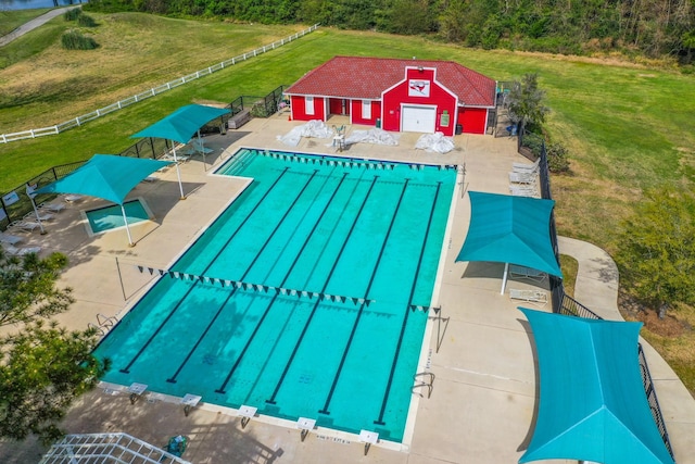 view of swimming pool with fence and a lawn