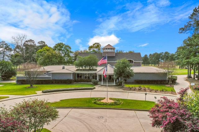 view of community with curved driveway and a lawn