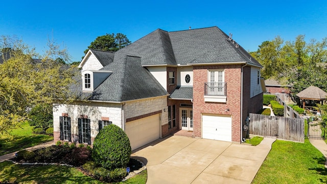 french country style house with a shingled roof, fence, concrete driveway, and brick siding