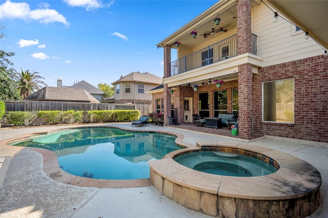 view of swimming pool with a patio area, a pool with connected hot tub, fence, and a ceiling fan