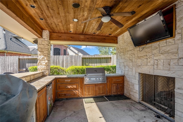 view of patio featuring a ceiling fan, grilling area, fence, and an outdoor kitchen
