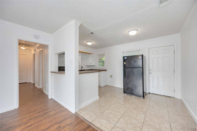 10522 Fairland Dr, Houston, TX 77051 - kitchen with a textured ceiling, visible vents, crown molding, and freestanding refrigerator