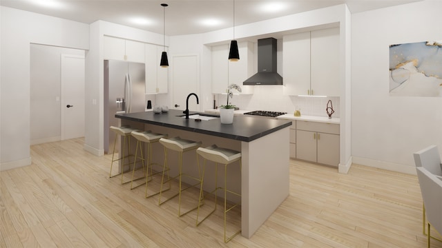 1128 W Pierce St, Houston, TX 77019 - kitchen featuring wall chimney range hood, a sink, light wood finished floors, and a kitchen bar